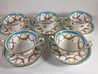 Five antique bouillon bowls with matching saucers placed together showing design and condition.