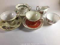 Three Aynsley tea cups and saucers and Aynsley April Rose cream and sugar set displayed on a white surface, showcasing all items in the lot.