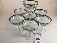 Photo of all eight crystal sherbet dishes arranged in a pyramid shape, showing clear glass and silver rims
