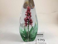Front view of clear glass sculpture featuring a carved orchid with red petals and green leaves inside, signed by Mats Jonasson.