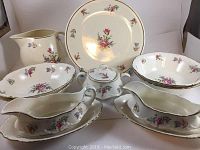 Full set view showing serving plate, picture plate, oval dishes, gravy boats, and sugar bowl all with floral pattern and gold trim