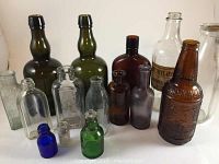 Overview of 15 assorted glass bottles in various colors and sizes