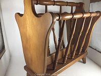 Side view of the wooden magazine rack showing the handle and spindle side panels.