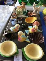Overview photo showing the majority of ceramic items arranged on a table, including animal figurines and bowls.