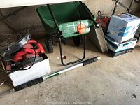 Photo showing Scotts Standard seed spreader, various power tools including circular saws in a white box, and long handled attachments such as gutter cleaner and other tools