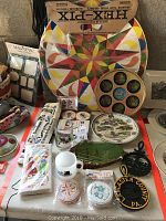 Overall photo of assorted PA Dutch items including wooden game, kitchen towels, decorative plates and magnets.