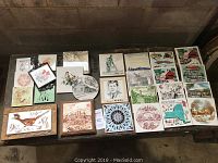 Full display of 26 decorative tiles on a table showing diverse designs including landmarks, animals, and artistic patterns.