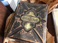 Holy Bible with heavily worn embossed leather cover showing gold lettering and decorative design with extensive edge wear.