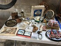 Lot overview showing wooden Mayflower model kit, coasters, plaster Flemish waterfront casting and various small decorative and household items on a table.