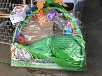 Photo showing original packaging of Rainforest Melodies Lights Deluxe Gym baby play mat in green with multiple colorful hanging toys and arches.
