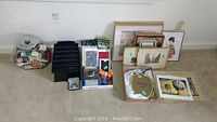 Wide shot showing collection on floor including matchbooks in containers, framed art prints, cards, and decorative items packed together