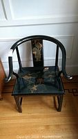 Front view of solid wood occasional chair with curved arms and floral decoration.