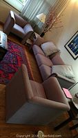 Living room setup featuring Krug sofa and two side chairs arranged around a rug with a lamp and decoration in background.