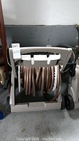 Front view of hose caddy with garden hose coiled inside, showing wheels and handle