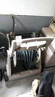 Side view of the garden hose coiled on a beige plastic reel caddy with wheels and handle.