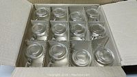 Top view of one box showing 12 handled clear glass mugs packed in individual cardboard compartments.