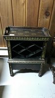 Front angled view showing the full wine rack with carved features, diamond bottle holders, and removable decorated top tray with side handles.