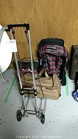Longchamps duffle roller bag, expedition backpack, and additional bags arranged with a folding luggage cart in front