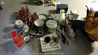 Overview of all kitchen items laid out on table showing various glassware, juicers, pitchers, storage containers, and stainless steel steamer box