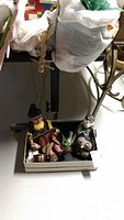 Two marionette/figurine pieces on a tray, one a seated grandmother marionette and the other a smaller hooded figure
