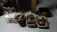 Wide shot of the metal plant stand, multiple wicker baskets, and some baskets containing faux fruit, all displayed on floor.