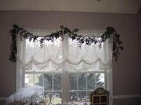 Wide window with white lace scalloped valance and lace panels draped in scallops