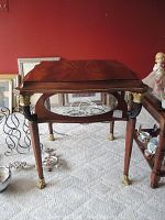 Full view of antique wooden table with carved legs and brass metalwork, glass shelf below.