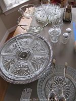 Glassware array top view showing serving trays, chip and dip bowls, salt and pepper shakers on table with window light