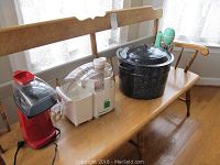 Photo showing all four items placed on wooden bench: red electric popcorn popper, white Juiceman Jr juicer, large black speckled canning pot, green vintage Hamilton Beach Drink Master mixer.