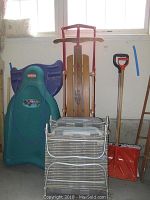 Photo shows assembled lot including Flexible Flyer wooden sled with red handle bars, Rubbermaid Icy Rider sled, orange and red snow shovels, and four folding lawn chairs stacked.