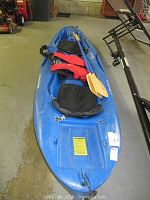 Front-angle view of blue sit-on-top kayak with paddles and life vests placed inside
