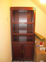 Front view of the wooden cabinet with closed bottom doors and two open shelves above in a dark brown finish.
