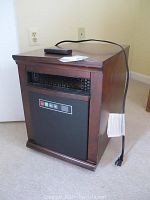 Twin Star infrared electric heater with wooden casing and remote control on top, angled left side view.