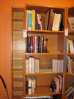 Wide view of wooden bookshelf filled with assorted books in various sizes and colors