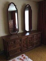 Front view of full wooden dresser with 2 mirrors above on the wall, showing dresser and mirror design