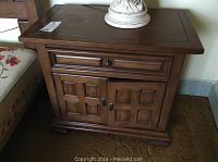 Front view of wooden night stand with drawer and cabinet doors closed