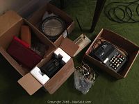Full view of the lot showing various items including Commodore calculator, boxed items, and assorted electronics in open boxes on floor.