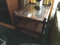 First photo showing one of the wooden end tables with a glass top inset over cane, wooden legs with rounded corner finials.