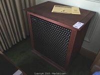 Front and side view of the speaker cabinet showing wood finish and grille