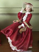 Front angle of Royal Doulton figurine showing woman in red dress and hat with multicolored shawl.