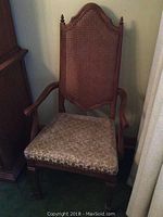 Front view of a wood frame chair with a tall cane back and upholstered seat, showing the overall style and condition.