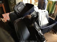Multiple dark blue plastic storage bins with gray lids in partially stacked arrangement. Some bins are filled with lids and other items.
