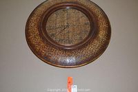 Front view of a large round wall clock with ornate golden brown metal frame and glass cover.