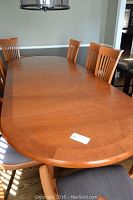 Extended table top with removable leaves installed, surrounded by chairs