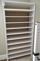Front view of a tall white shoe rack with multiple shelves for shoes.