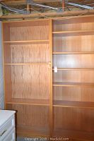 Photo of two tall oak-like bookcases with shelves placed side by side, showing front view and wood grain details.