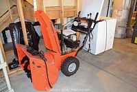 Side view of entire snowblower showing auger housing, engine, wheels and handlebar
