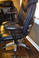 Side view of black leather office chair showing padded armrest, seat, and backrest.