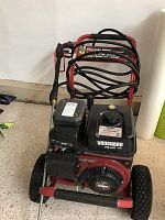 Front view showing complete red frame, two wheels, black engine and coiled hose