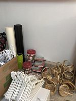Photo showing white plastic hangers, various sizes of foam rollers (white and green), small red and white IKEA storage boxes, and a collection of wicker baskets on the floor.
